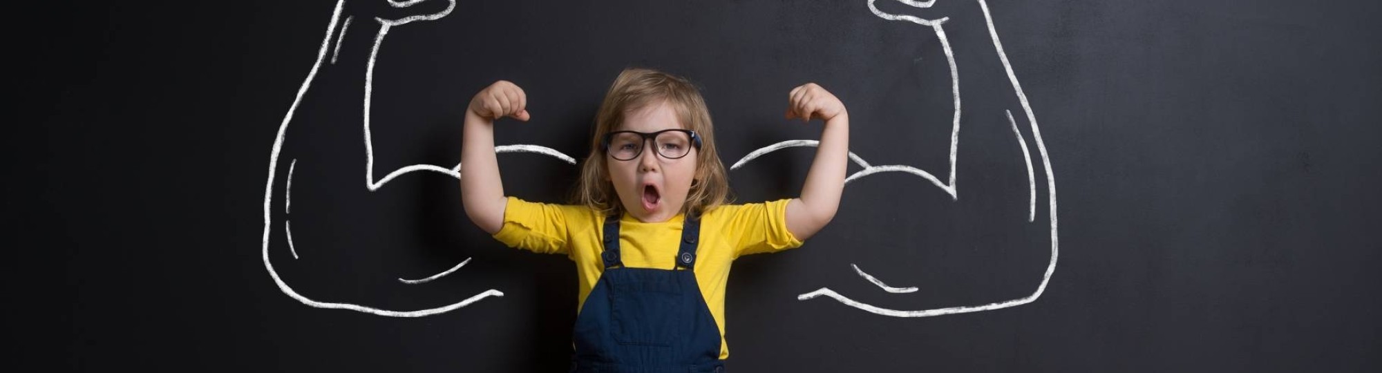 meisje laat spierballen zien voor schoolbord