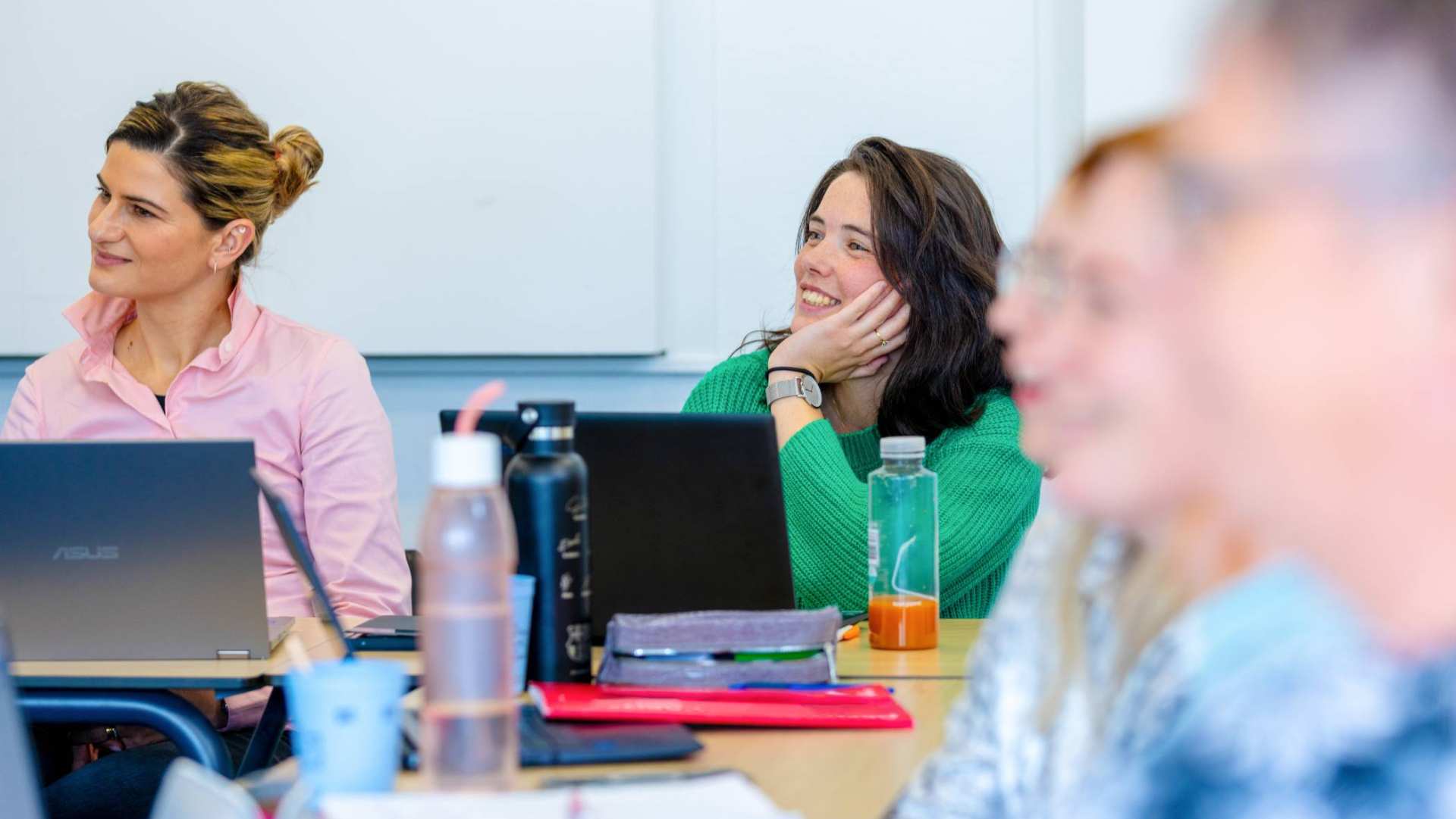 Student in groene trui is aan het lachen tijdens opleiding technische thuiszorgverpleegkundige