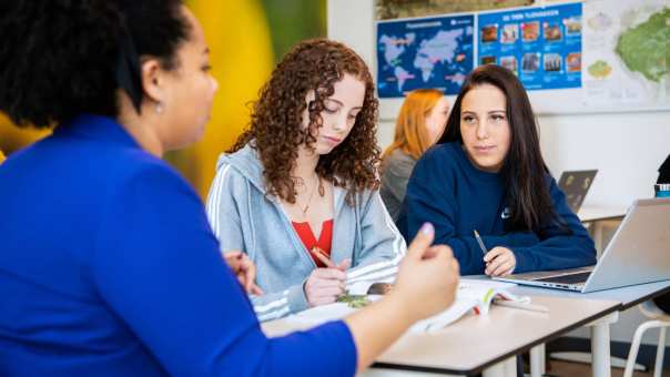 2 leerlingen krijgen uitleg aan tafel van een docenten op het Citadel College. 