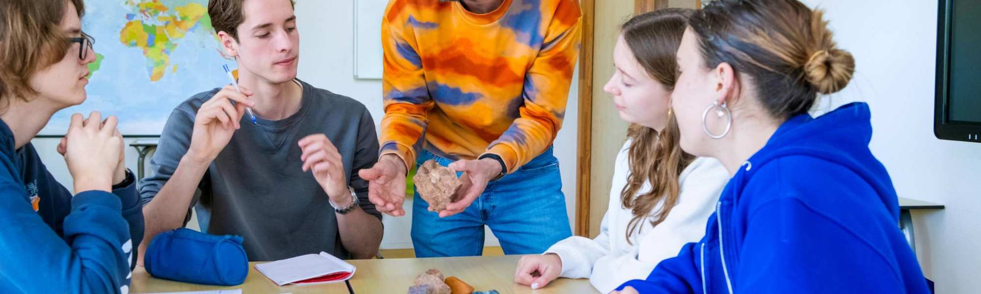 De leraar vertelt aan de studenten over een steen. 