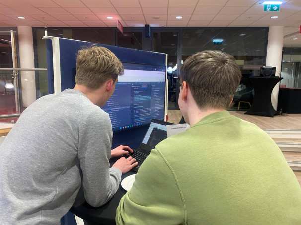 2 studenten achter een laptop tijdens de alumni-bijeenkomst van CMD en HBO-ICT