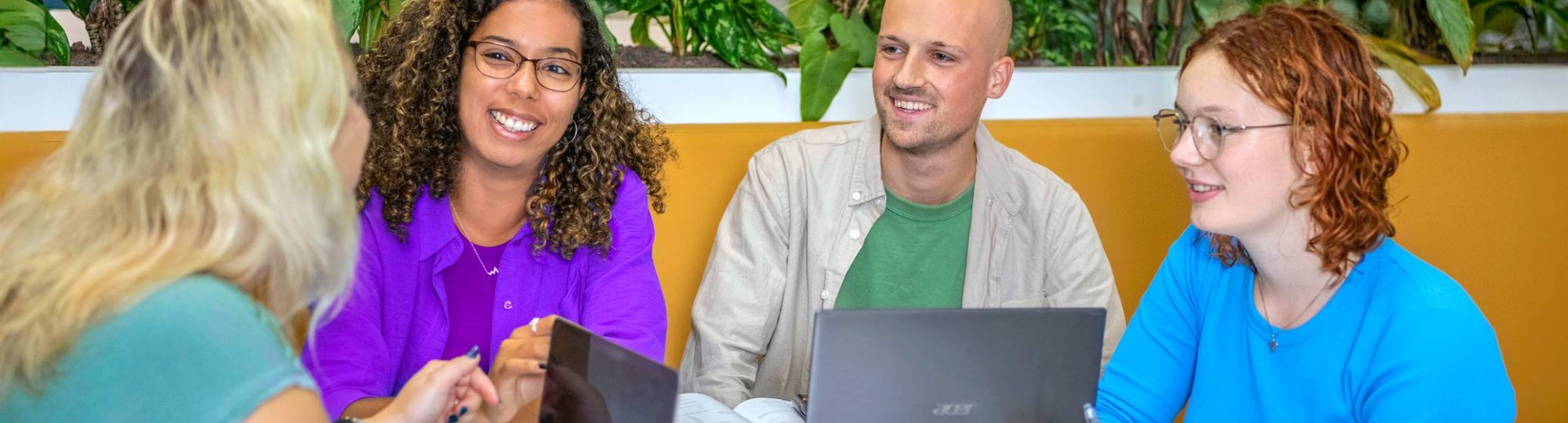 Twee studenten maken in een klaslokaal een papieren ster met allemaal verschillende kleuren.