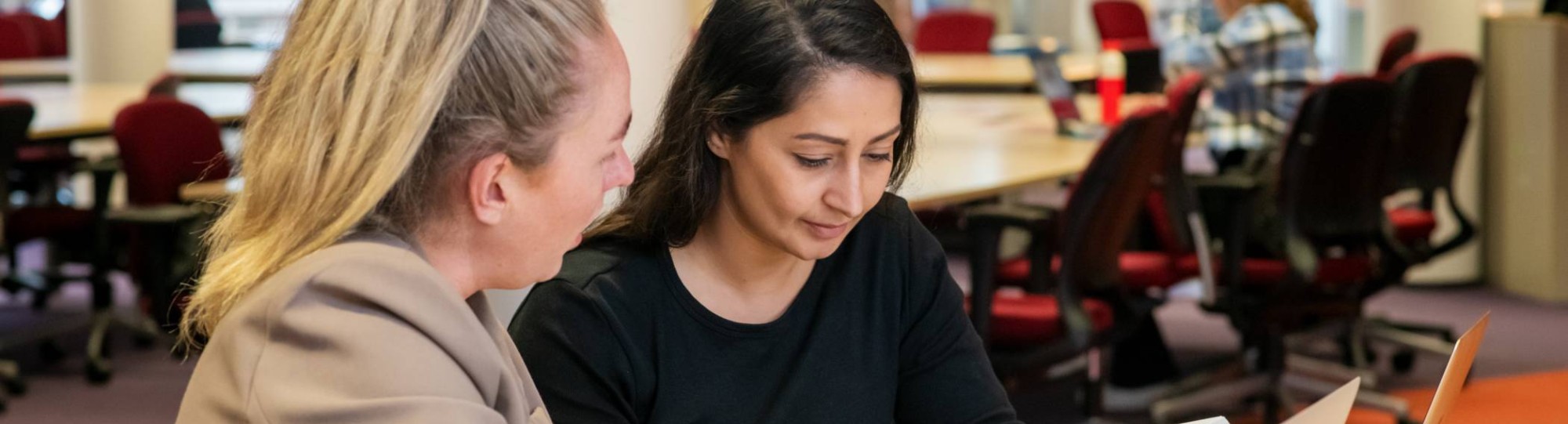 Twee studenten aan het werk in de bibliotheek en kijken naar een boek voor studie PMT deeltijd