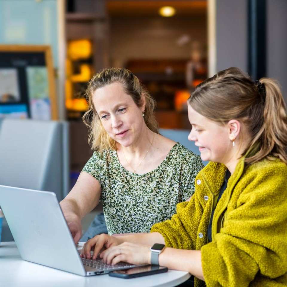 2 studenten zitten achter de laptop te werken in de kantine