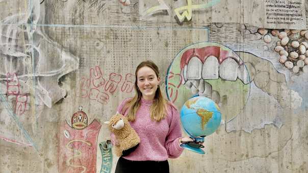 Iris Klein. student Mondzorgkunde met een wereldbol en een knuffel van een lama in haar hand. 