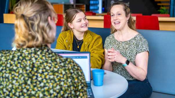 3 studenten met elkaar in gesprek over Verpleegkunde achter de laptop