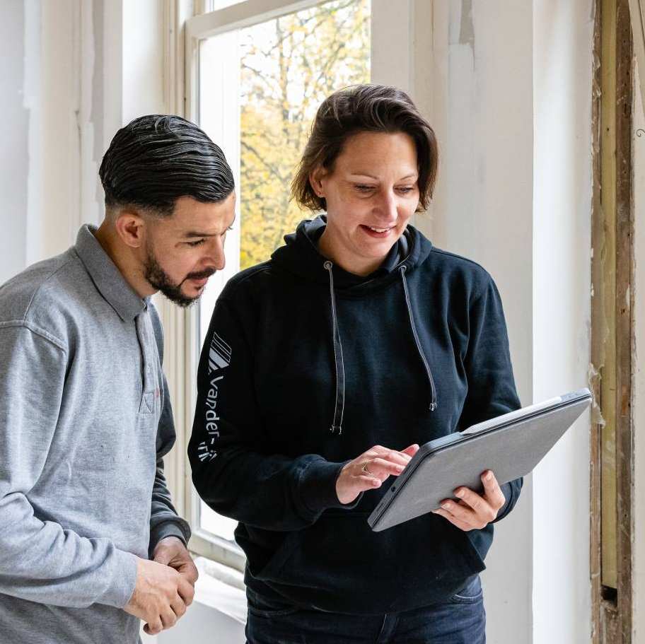 bouwkundige bespreekt bij een venster de voortgang met een medewerker