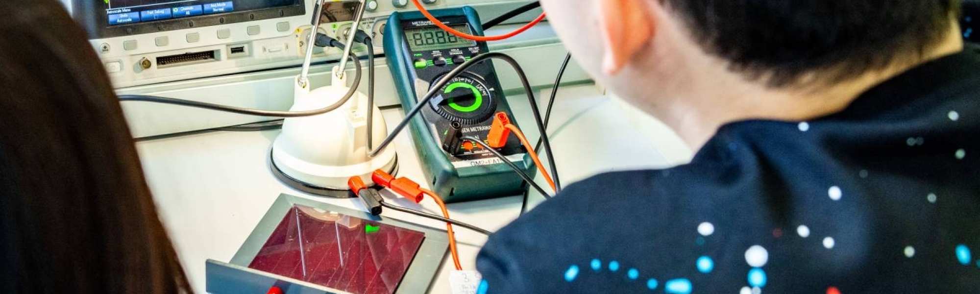 Twee studenten elektrotechniek doen een experiment met een zonnepaneel.