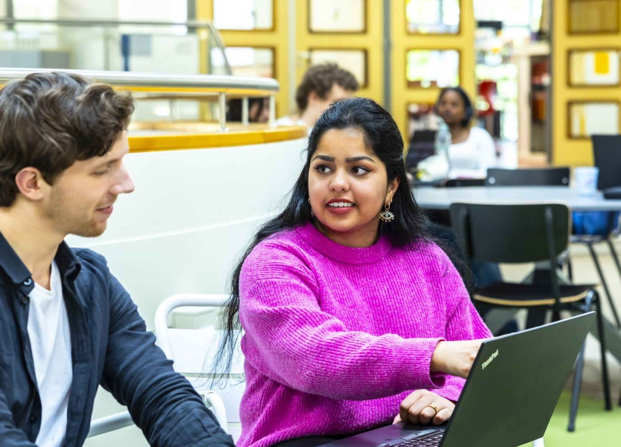 2 ICT-studenten overleggen met elkaar bij een laptop.