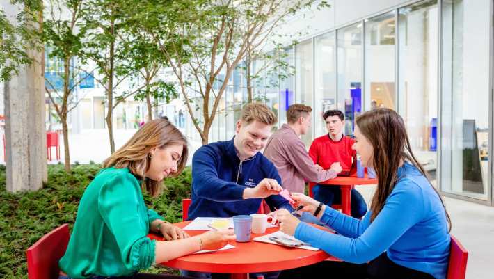 Student overhandigt kaartje aan andere student. Master Circulaire Economie 2024.