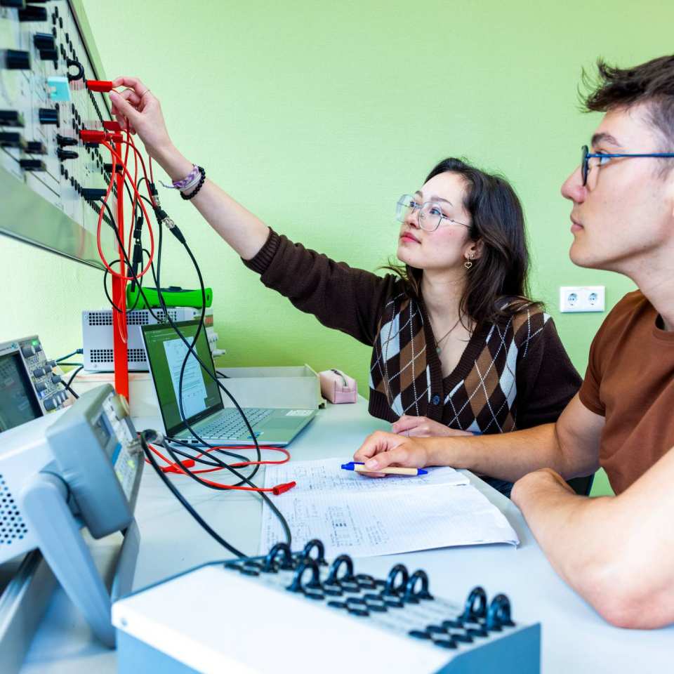 Twee studenten elektrotechniek werken samen tijdens een practicumsituatie.