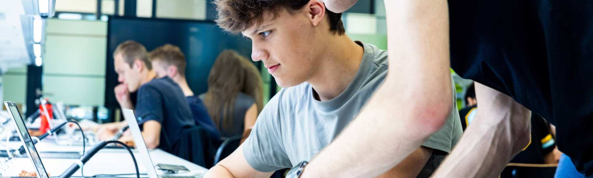 Studenten embedded systems engineering werken samen op de laptop in het lab.