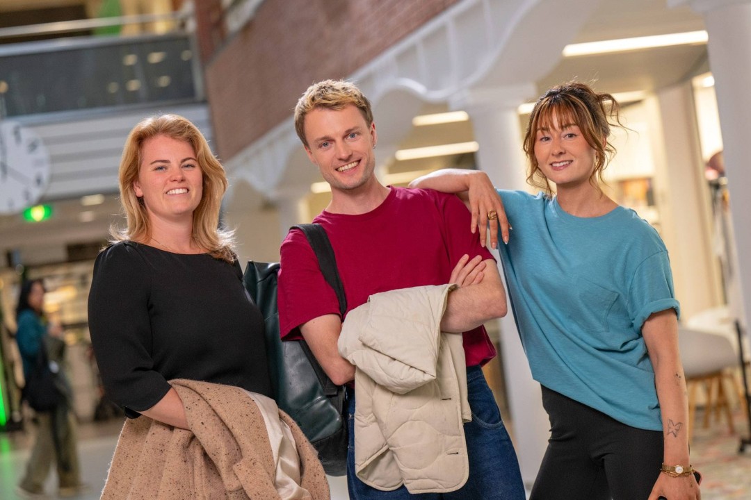 Groep studenten staat in hal met jassen uit en lachen
