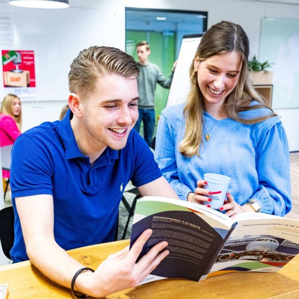 Twee studenten Facility Management kijken in een studieboek in Nijmegen