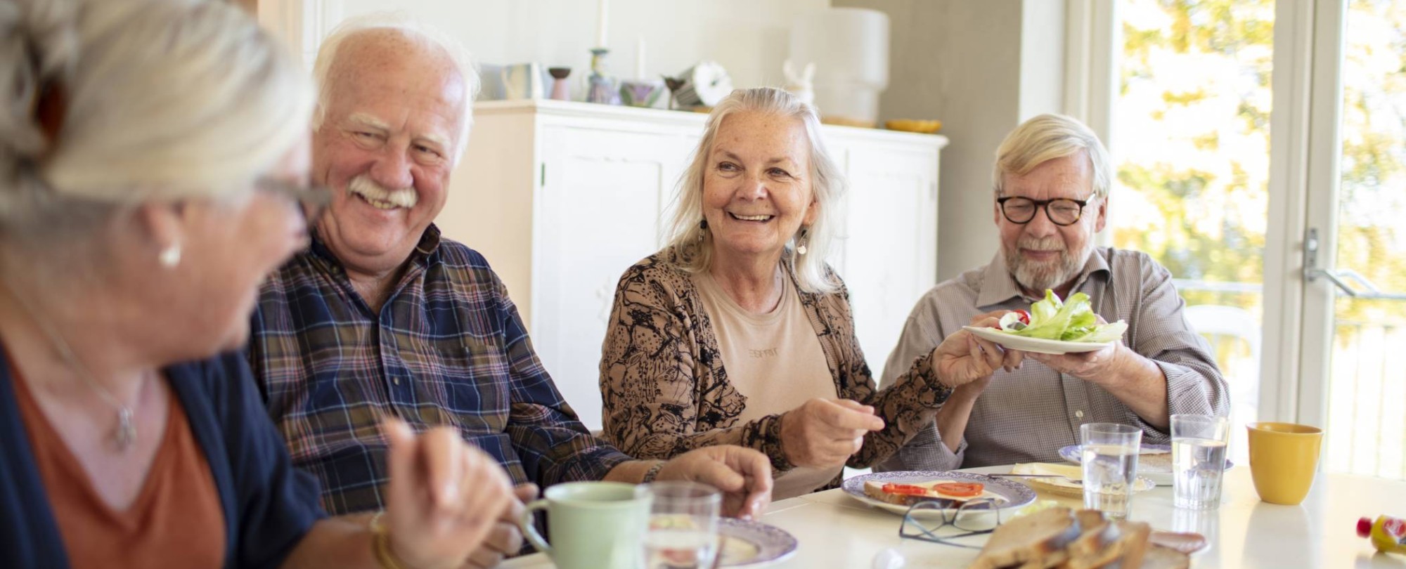 Groep ouderen aan tafel tijdens het ontbijt in een verpleeghuis
