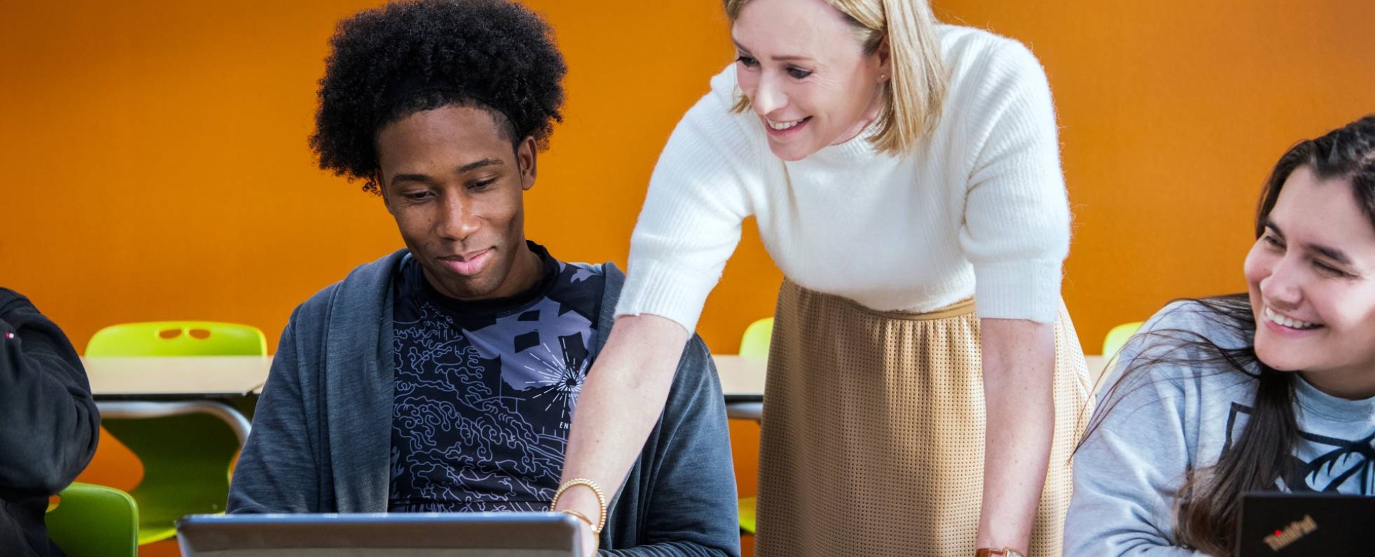 Docent legt masterstudenten wat uit en wijst op laptopscherm