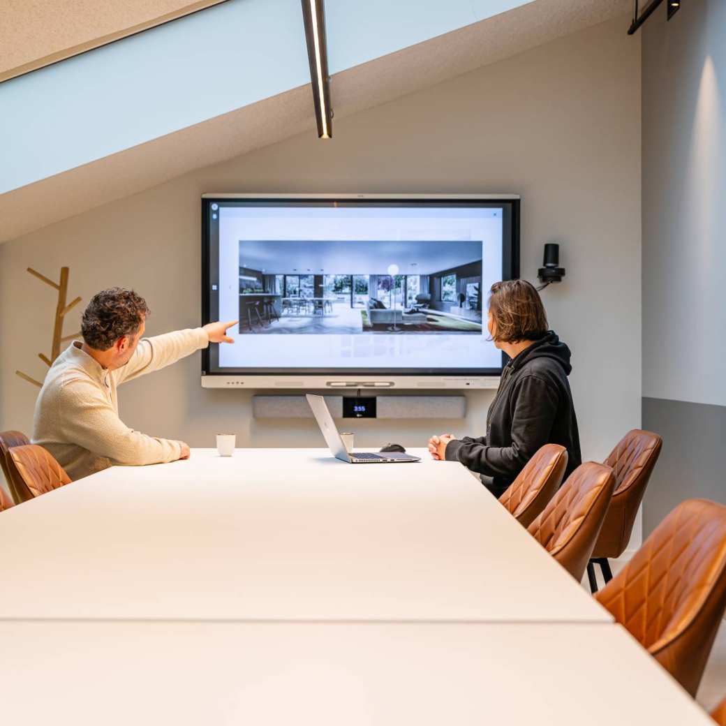 2 personen overleggen voortgang bouw bij een digibord