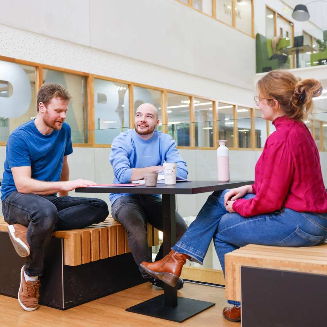 3 mensen in overleg aan een tafel