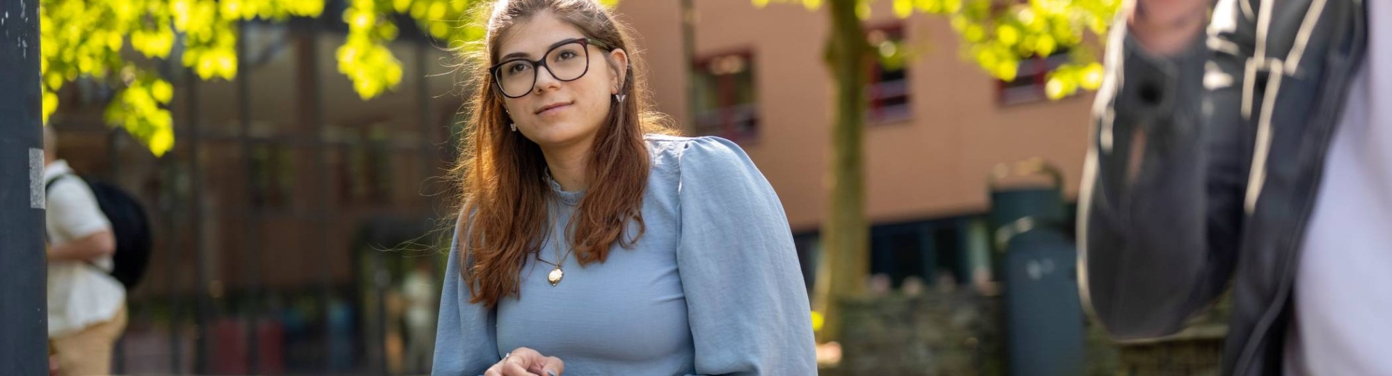 Portretfoto van studente buiten zittend op een bankje bij K33, in de pauze. 