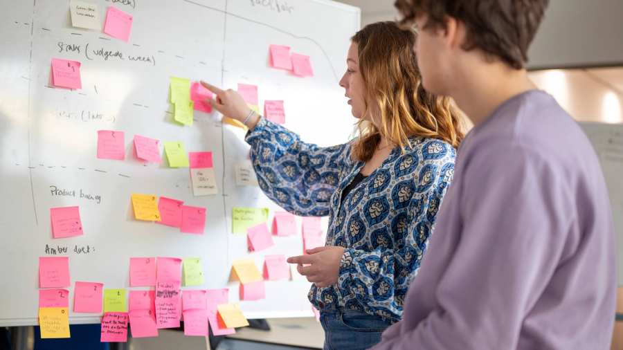 studenten plakken post its voor tijdlijn aanmelden