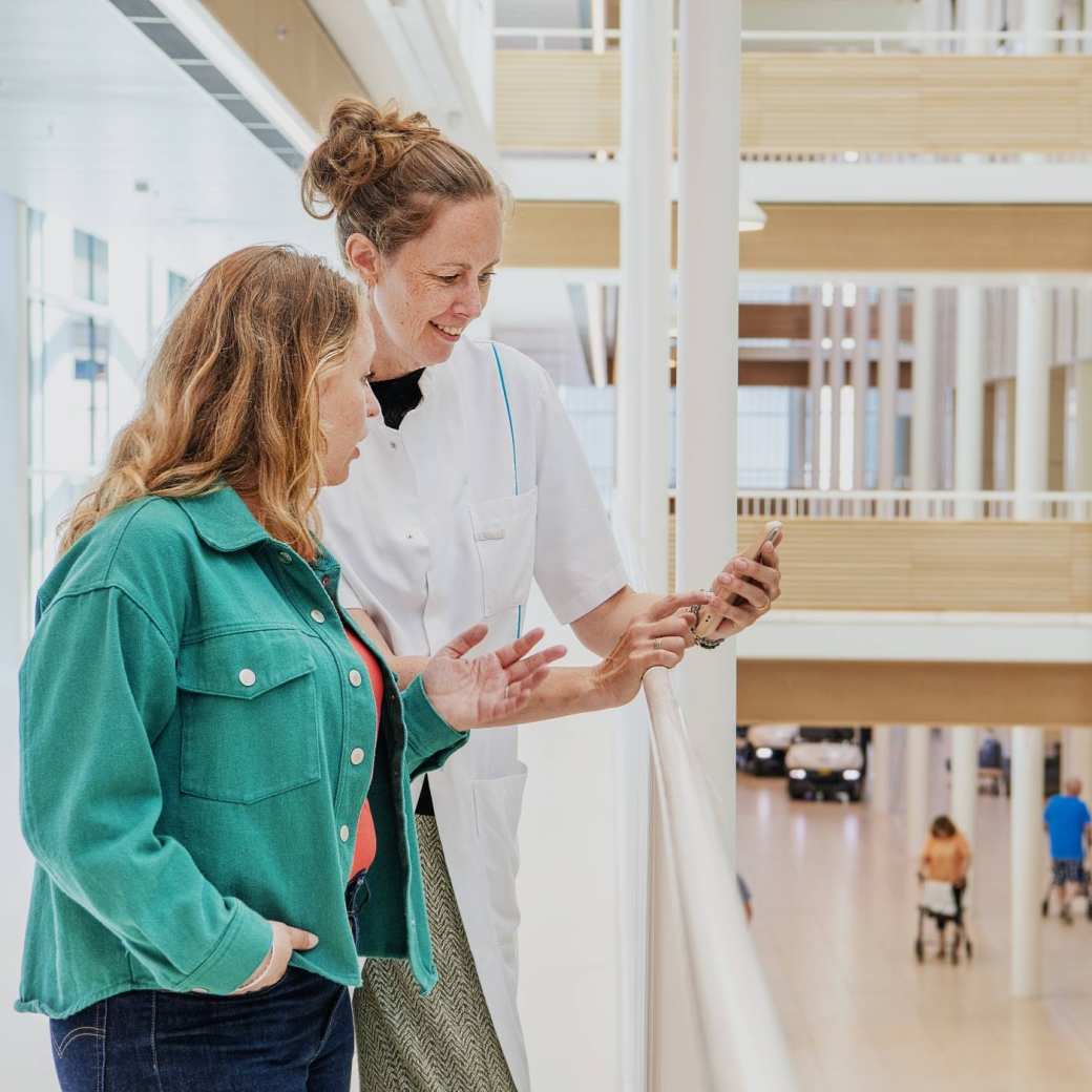 Zorgprofessional laat op telefoon iets zien aan collega