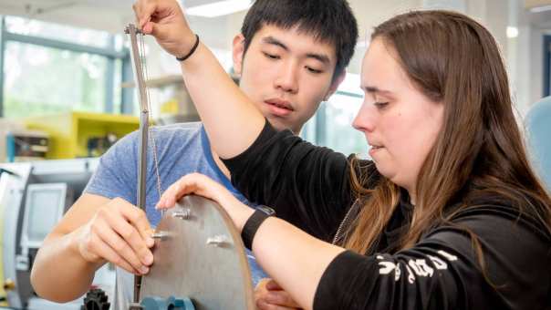 Twee studenten werktuigbouwkunde werken samen aan een kartrol.