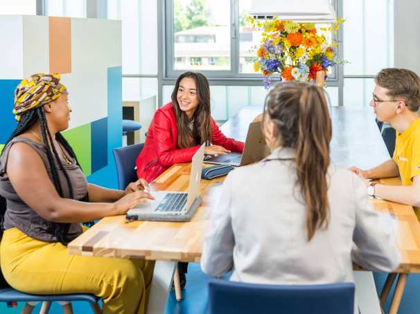 Lo-res. Groep van 4 studenten in overleg aan tafel in algemene ruimte HAN. 