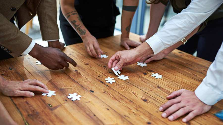 Op een vierkante houten tafel samen een puzzel leggen. Puzzelstukjes, samenwerken, seece