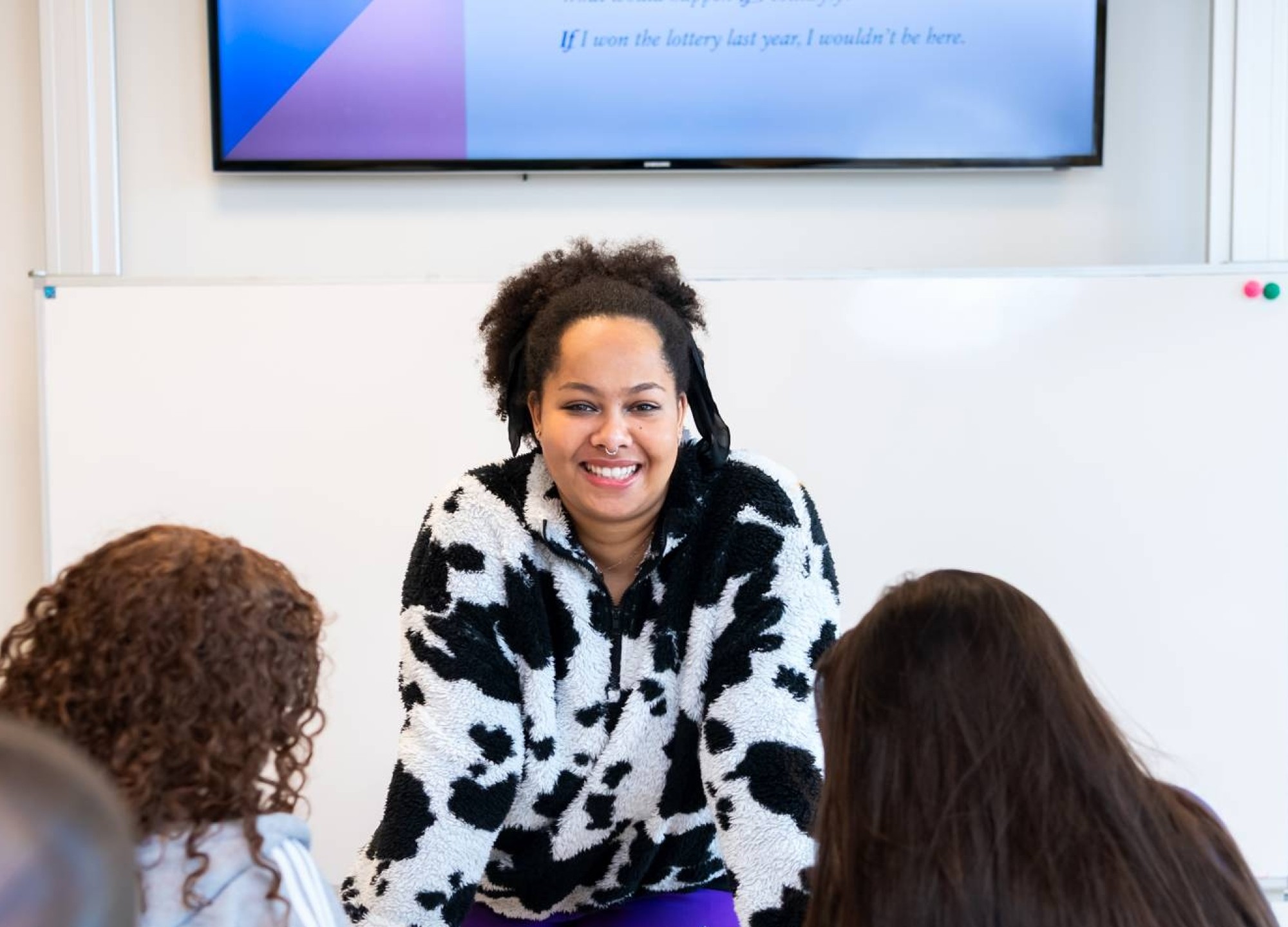 Docente Angel Olatunji leunt voorover op de lessenaar in een klaslokaal op het Citadel College. 