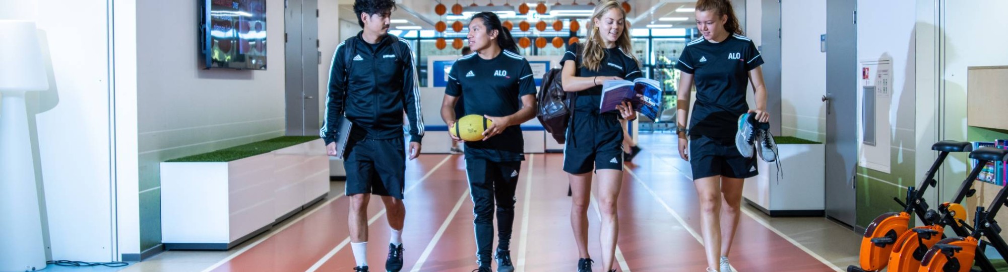 sportkunde en alo samen liggende foto studenten lopen over atletiekbaan binnen bij gymnasion veraf esteban selena carlijn randy 2022