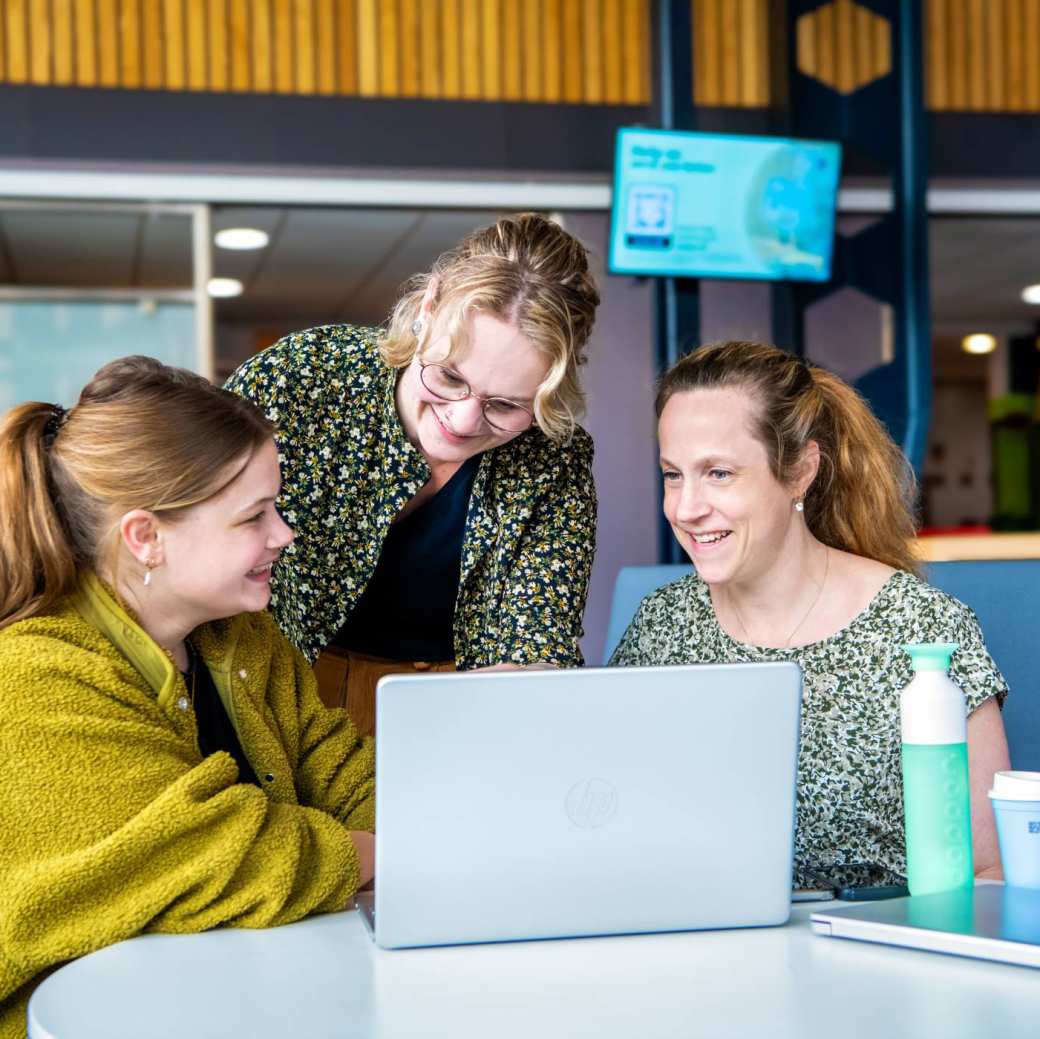 Drie deeltijdstudenten verpleegkunde overleggen met elkaar in de kantine.