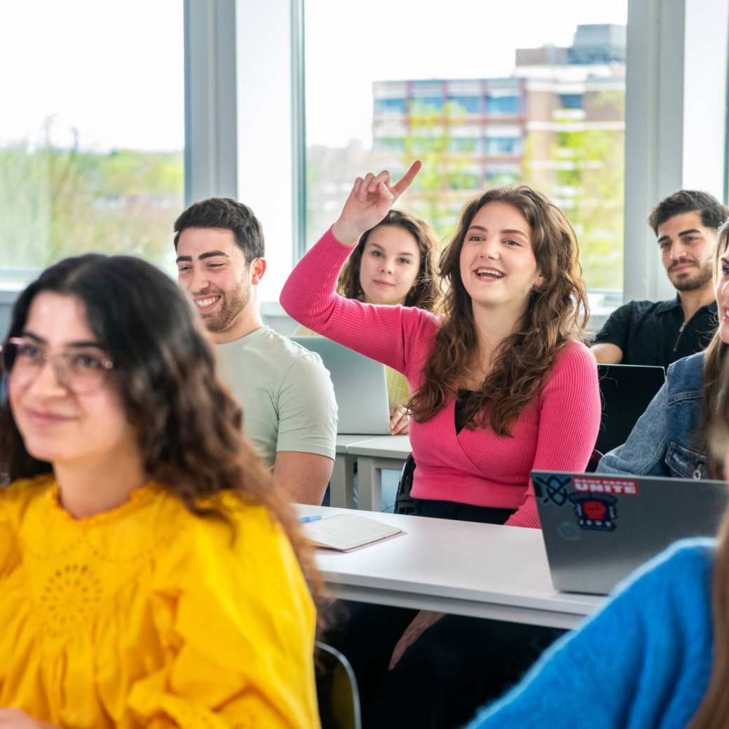 Bachelorstudent steekt vinger op tijdens de les in een klaslokaal.