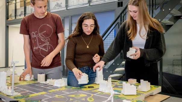 Drie studenten van de Master Engineering Systems Sustainable Energy werken aan de Smart Grid-tafel.