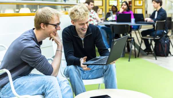 Twee hbo-ict studenten kijken samen lachend naar hun laptop