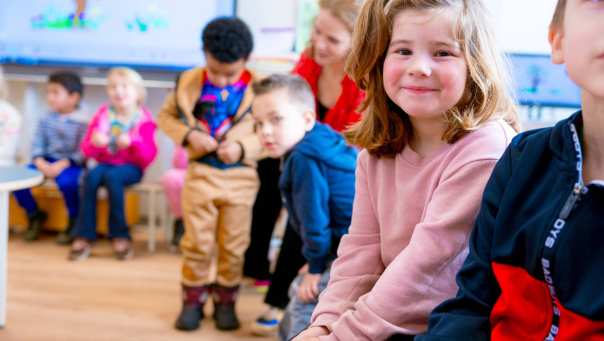 De kleuters op de school De Ommelander. De kleuters zitten in de klas op de stoelen. 