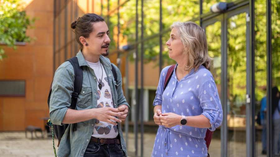 Docente praat met mannelijke student, buiten bij K33. Studentbegeleiding. 