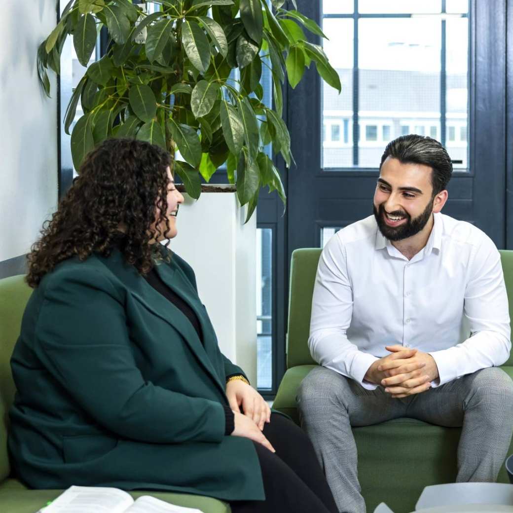 2 deelnemers aan een hbo-programma overleggen in een lounge op de HAN-campus.