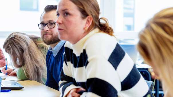 Vrouw met witte trui met zwarte strepen luistert naar presentatie. Op de groenewoudseweg, opleiding maag-, lever,- darmverpleegkundige.