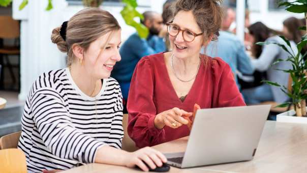 Docent in overleg met student met laptop