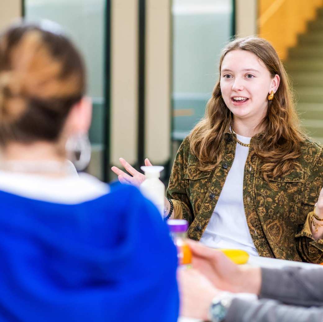 De student vertelt met twee handen in de lucht. 