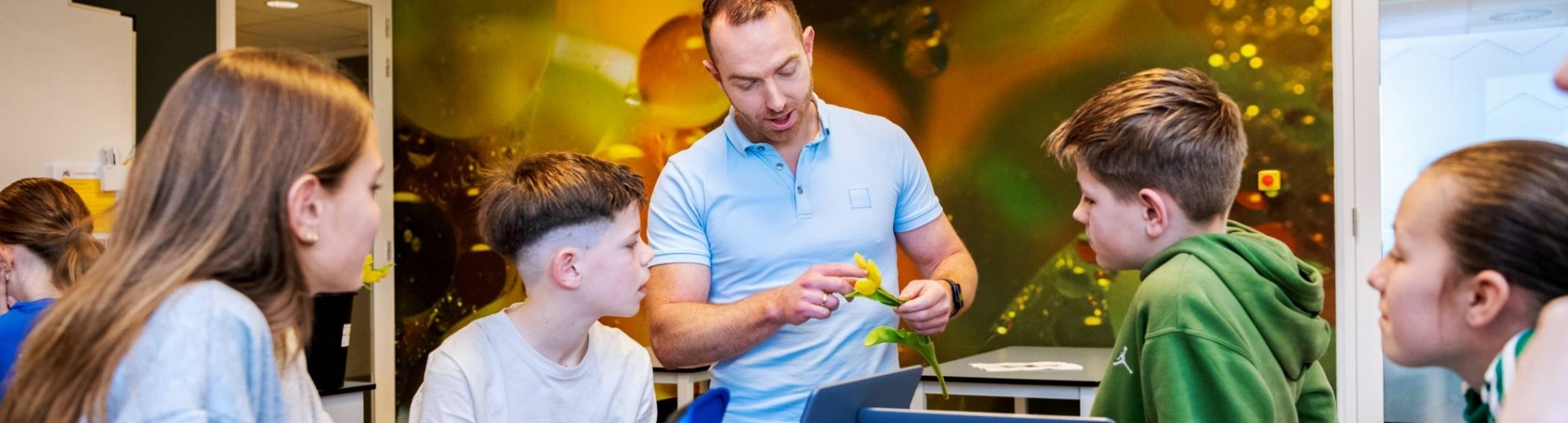 Docent Niels Janssen geeft uitleg over een bloem aan 4 leerlingen op het Citadel College. 