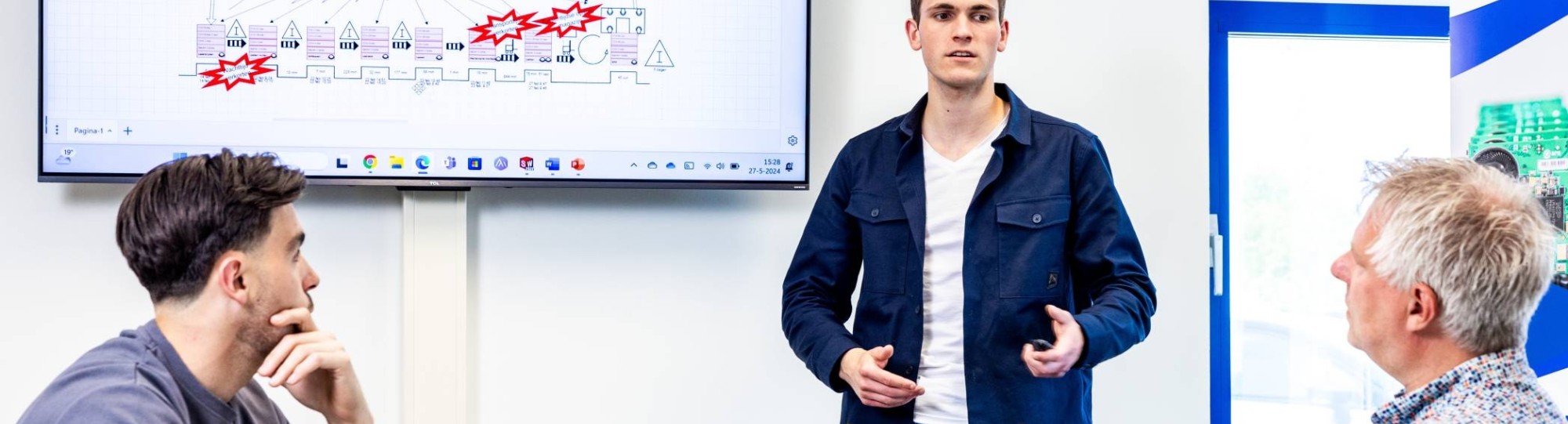 Een student Technische Bedrijfskunde geeft op de werkplek een presentatie over het selecteren en invoeren van nieuwe technologieën en innovaties in bestaande bedrijfsprocessen.