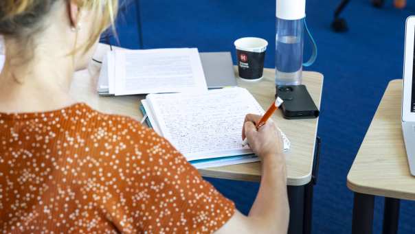 Student van de Master Social Work maakt aantekening met pen en papier.