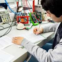 Een student elektrotechniek werkt aan een logboek tijdens het netwerkpracticum.