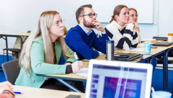 Man en drie vrouwen luisteren naar presentatie. Op de Groenewoudseweg. De opleiding maag-, lever-, darmverpleegkundige.