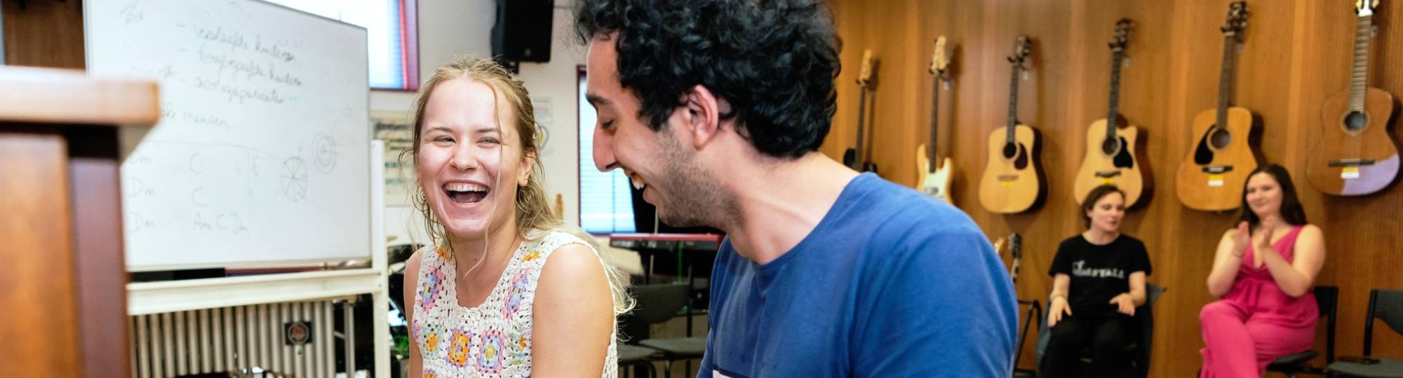 Twee studenten muziektherapie spelen samen op de piano tijdens een praktijkles