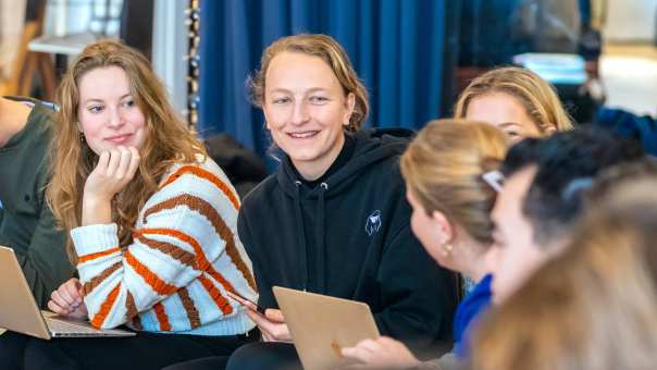 Studenten zitten samen, lachen met elkaar.