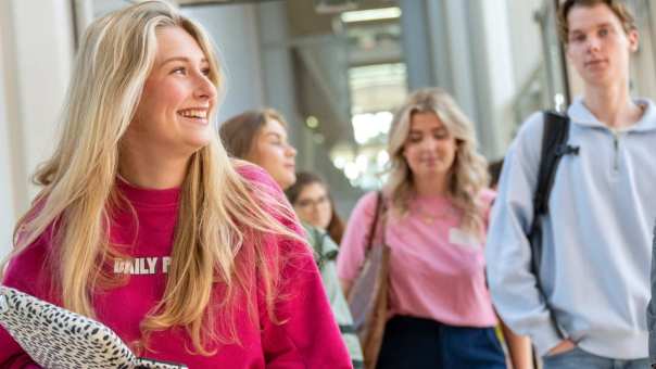 Groepje studenten lopen lachend door de gang van K35 naar K33. 