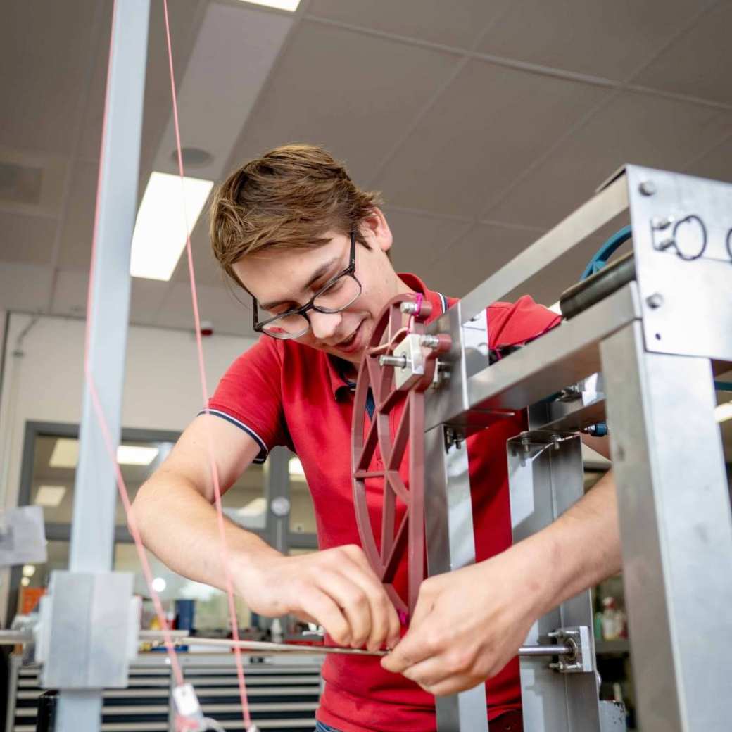 Een student werktuigbouwkunde werkt aan een industriële opstelling.