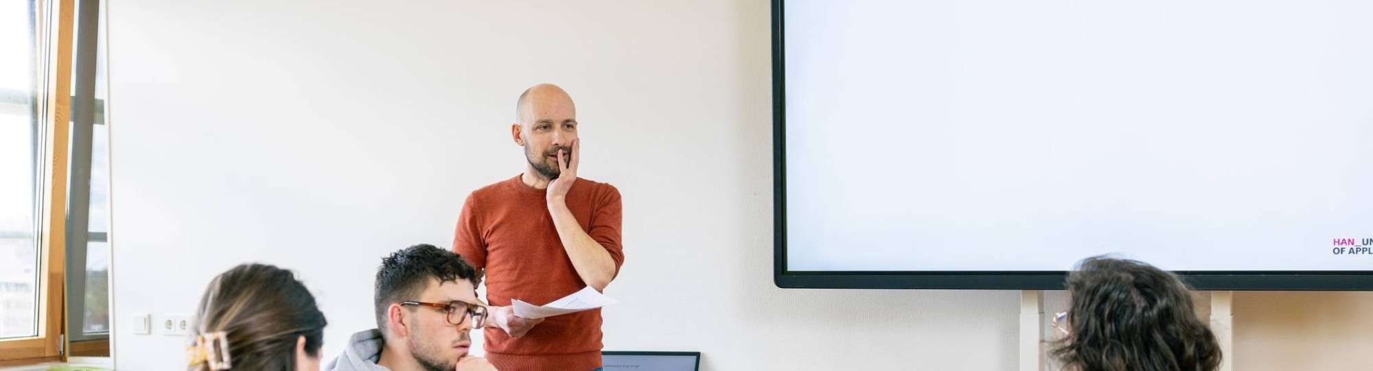 Twee studenten Leraar Nederlands bladeren door een boek in de mediatheek.